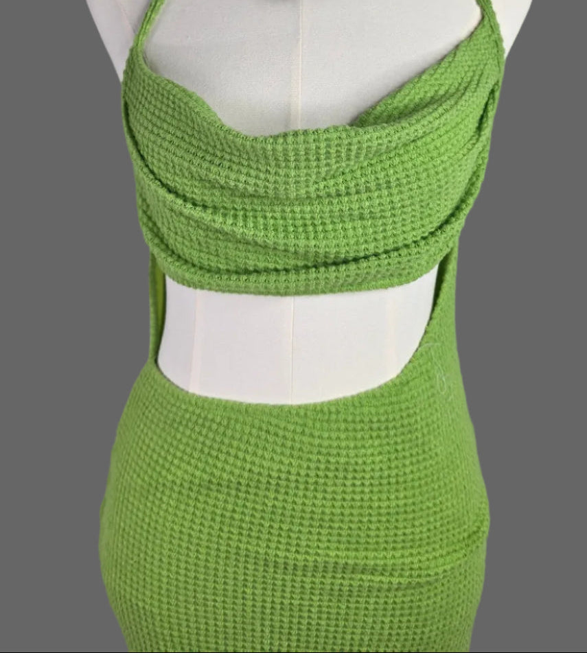A bright lime green textured knit two-piece set displayed on a white mannequin torso. The set includes a halter-style crop top with a draped wrap-front detail and a matching high-waisted, side-cutout pencil skirt.